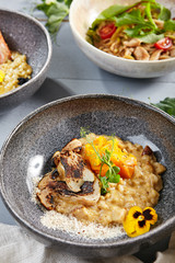 Risotto with white mushrooms and pumpkin in gray bowl