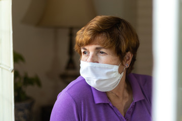 Elderly watches through the window of her house