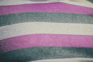 Detail of a fabric of a sweater in three colors - white, gray and pink.  Woven fabric in soft focus.