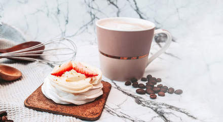 Baking banner. White dessert of meringue, cream and fresh strawberries, hot drink mug, open book and coffee beans on white marble surface