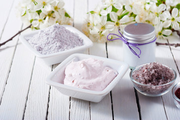 skin care product samples and cherry blossom on white wood table background