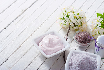 skin care product samples and cherry blossom on white wood table background