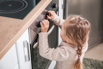 Little girl playing with electric oven at home