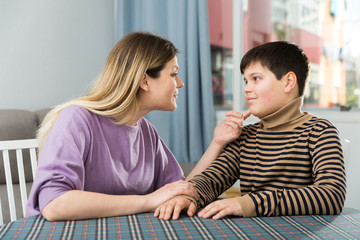 Portrait of young woman and son chatting at table