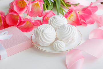 postcard. Marshmallows, pink tulips, satin ribbon on a white background