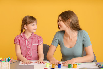 Fototapeta premium Drawing teacher giving private art lessons to little girl on color background