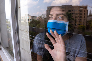 Woman watches through the window of her house