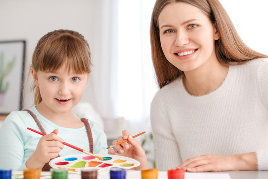 Drawing teacher giving private art lessons to little girl at home