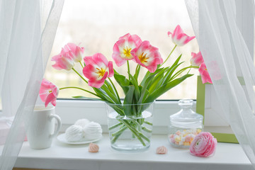 a vase of flowers is on the window a Cup of tea marshmallows, a good morning card