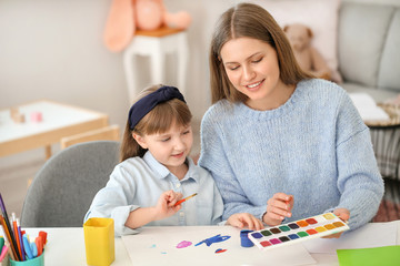 Drawing teacher giving private art lessons to little girl at home