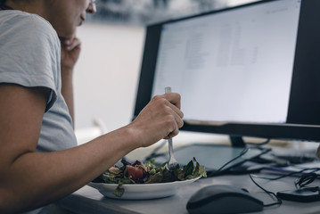 Woman eating salad while work from home. Busy people lifestyle.