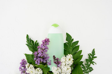 Cosmetic bottle close up with lilac flowers on white table with copy space