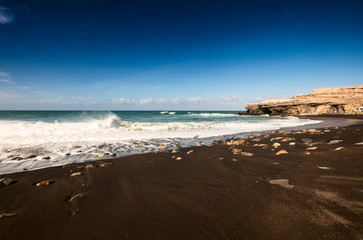 Black sand volcanic beach with wavea near fishing village Ajuy in Fuerteventura, Canary Islands, Spain