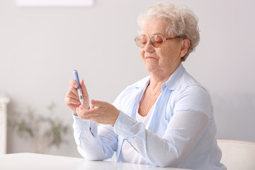 Diabetic senior woman measuring blood sugar level at home