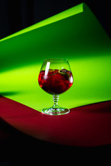 crimson colored cocktail on the gradient background of green and red