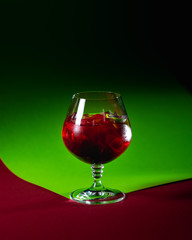 crimson colored cocktail on the gradient background of green and red