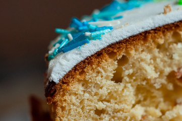 Easter cake poured with white icing and decorated with a confectionery blue sprinkle. Cooking Easter baking at home.