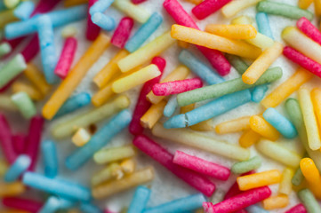 Multi-colored sweet pastry topping in white glaze decorates pastries. Close-up, macro shot.