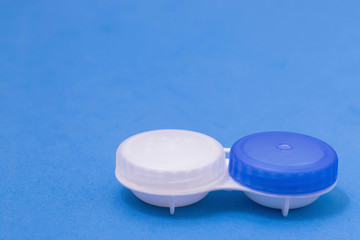 Contact lens container on a blue background. Storage o cleaning contact lenses for vision correction, place for text, copy space