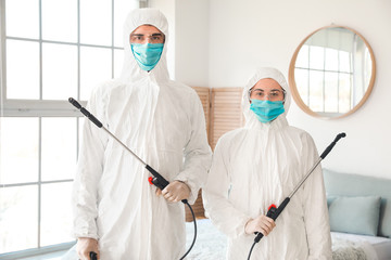 Workers in biohazard suits disinfecting house