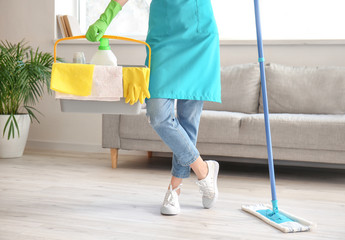 Young woman mopping floor in room