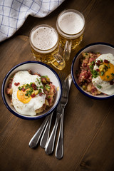 Norddeutscher Hamburger Labskaus mit Rindfleisch Corned Beef, Rote Beete, Kartoffeln, Saure Gurken, Spiegelei, Rollmops und Bier auf Holztisch