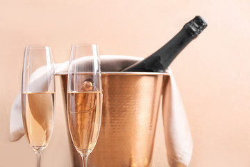Bucket with ice and champagne on color background