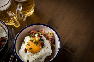Norddeutscher Hamburger Labskaus mit Rindfleisch Corned Beef, Rote Beete, Kartoffeln, Saure Gurken, Spiegelei, Rollmops und Bier auf Holztisch