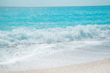 waves of Mediterranean sea running ashore , bright sunny day on beach, no people, glittering light in turquoise water