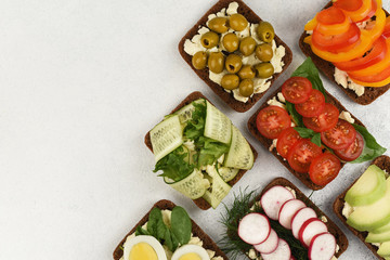 Top view set of vegetarian open faces sandwiches. Homemade vegetables sandwiches on light background with copy space. 