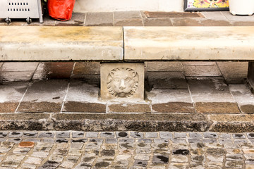 Stone bench in the Old City. Bas-relief of a lion's head on a support. Close-up. Winter season in Warsaw, Poland.