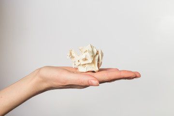 Crumpled white paper on a white background lies on a hand