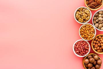 Nuts set in bowls on pink background top-down frame copy space mockup