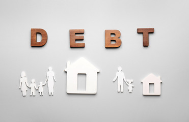 Figures of houses, family and word DEBT on grey background