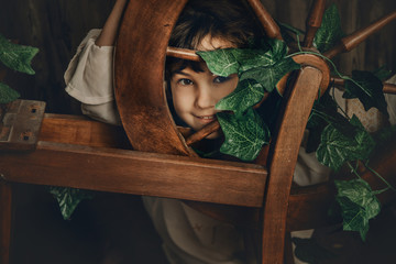 vintage portrait of young child girl with wool spinning wheel on wooden background