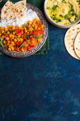 vegan food, hummus, rice, chickpeas with vegetables, pita bread on a blue background