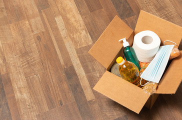 Donation goods in carton box on the floor. Pasta, toilet paper, medical mask, sunflower oil, sanitizer, caned food, bread. Food delivery for those who need.