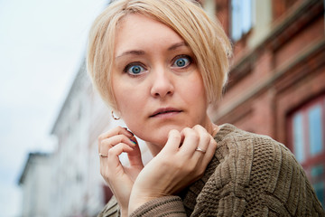 Blonde funny pretty girl near wall with red brick in Central part of old city. Portrait of girl on street