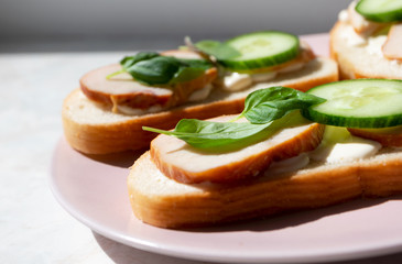 Close-up on sandwich with ham, basil leaves and cucumber. Details of food