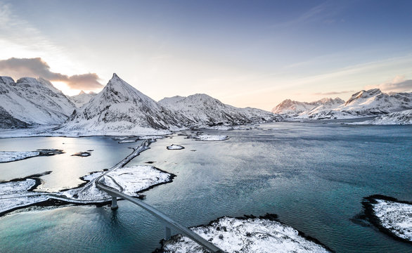 scenic view over a fjord and a village with streets in norway during winter with a drone