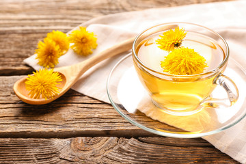 Cup of healthy dandelion tea on wooden background