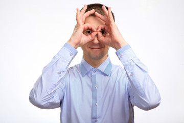 successful happy man shows the gesture OK with two hands, in a blue light casual shirt, staring at the camera. Isolated