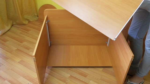 Man is trying parts of computer table after collecting sliding mechanism, closeup. Repairman is collecting furniture himself at home and making renovation.