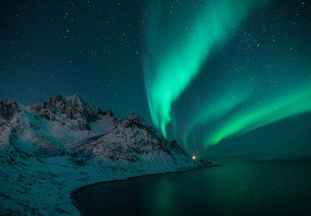 polar lights also called northern lights or aurora borealis in northern norway during winter above a fjord and snow covered mountains