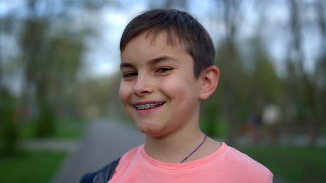 Joyful teen boy looking camera in park. Laughing guy in brackets posing outdoors