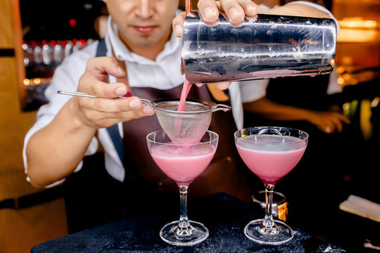 Bar tender preparing a cocktail pink drink pouring the alcohol, Bartender preparing different cocktails mixing