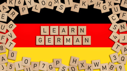 Learn German word written with wooden tiles over German flag.