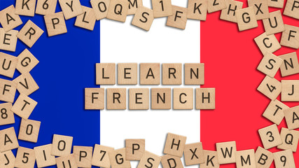 Learn French word written with wooden tiles over French flag.