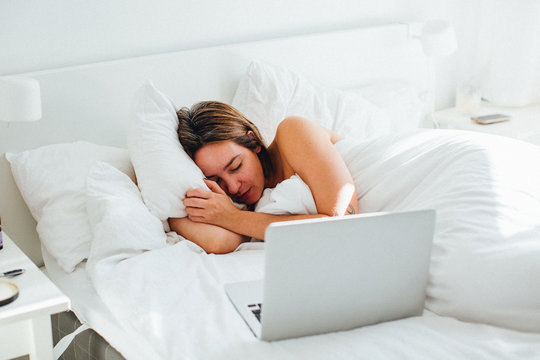 Woman Sleeping With Laptop On Bed At Home