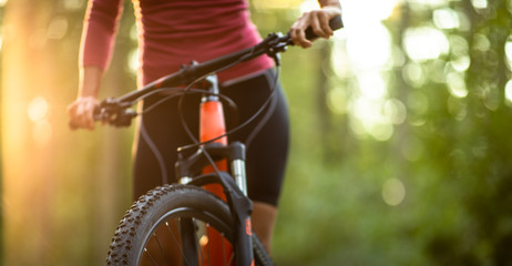 Pretty, young woman biking on a mountain bike enjoying healthy active lifestyle outdoors in summer (shallow DOF)